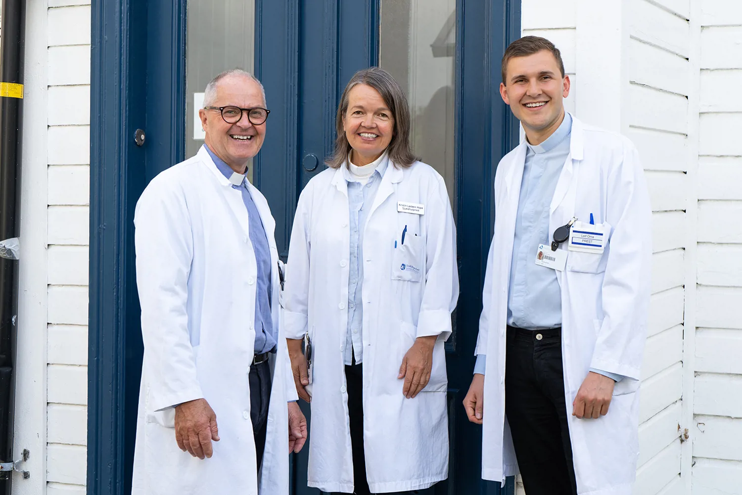 A group of people in white coats standing in front of a blue door