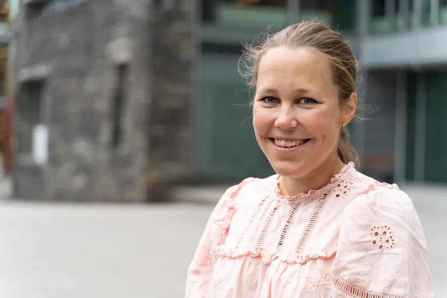 Smilende kvinne foran et bygg