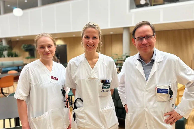 A group of people wearing white lab coats and badges