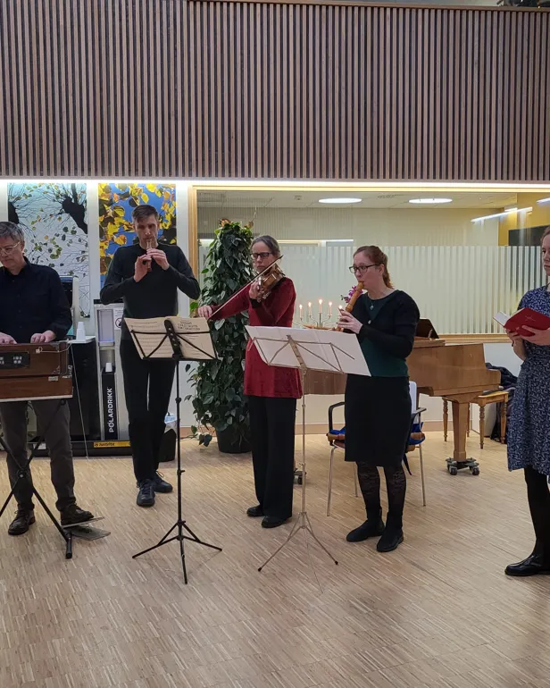 En gruppe mennesker som står i et rom med en scene og en mikrofon