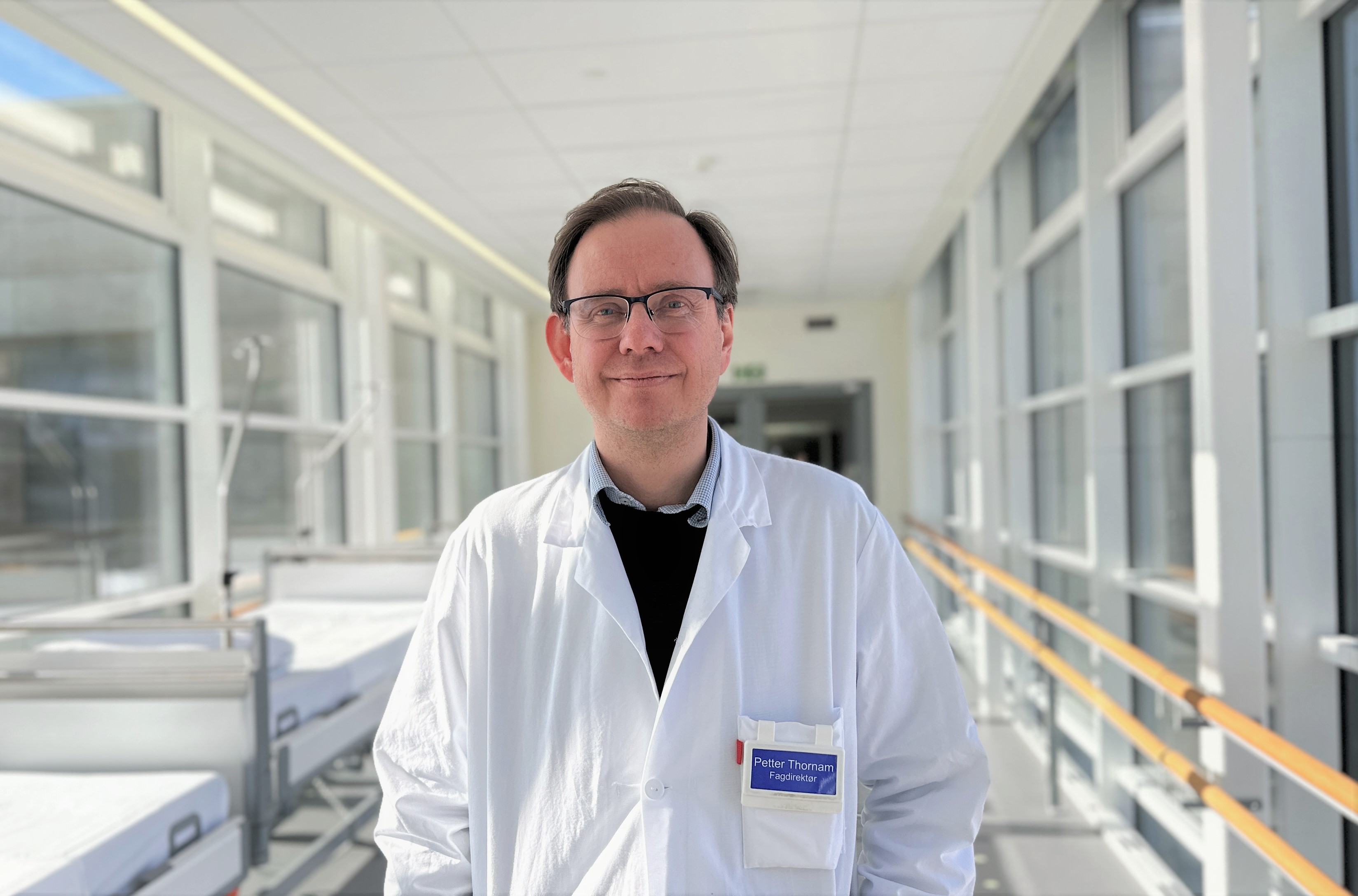 En mann iført hvit frakk og briller