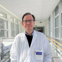 En mann iført hvit frakk og briller