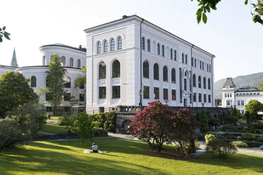 En hvit bygning med trær og gress