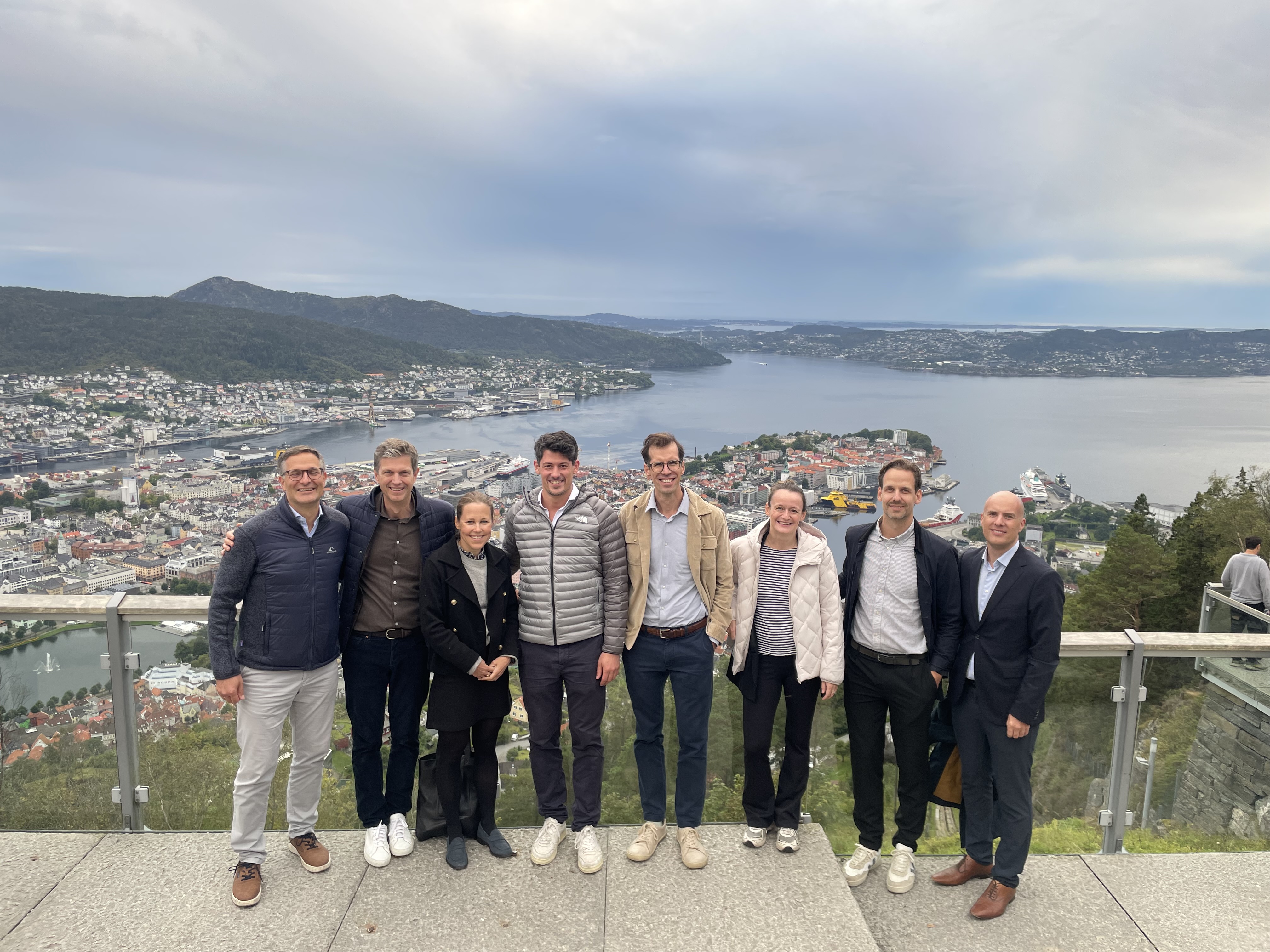 En gruppe menn poserer for et bilde på en bro over vann