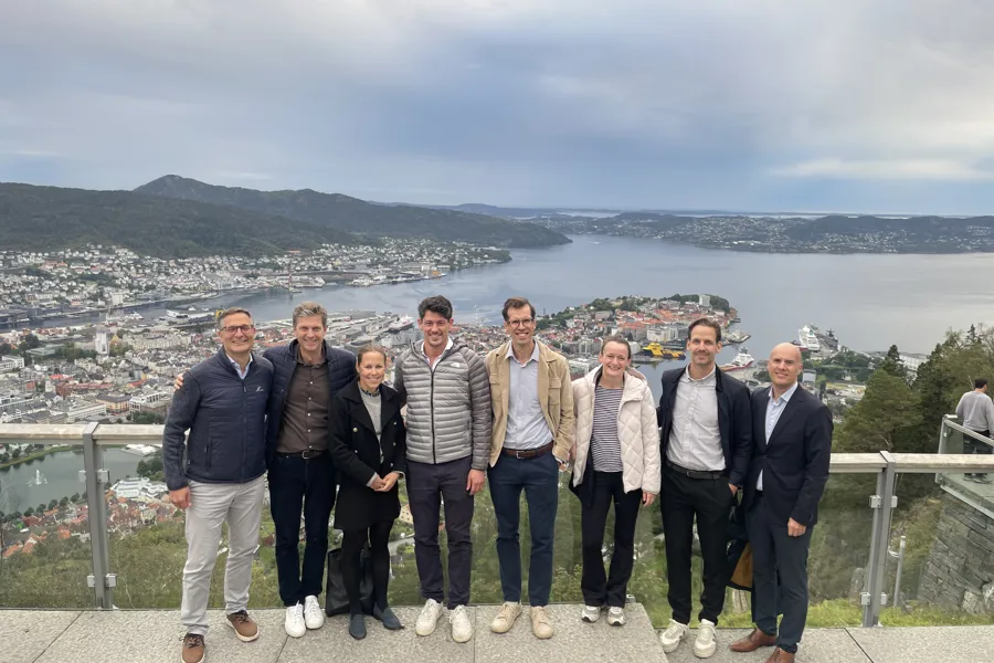 En gruppe menn poserer for et bilde på en bro over vann