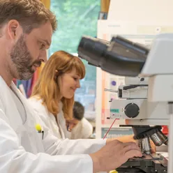 En mann og en kvinne som ser på et mikroskop
