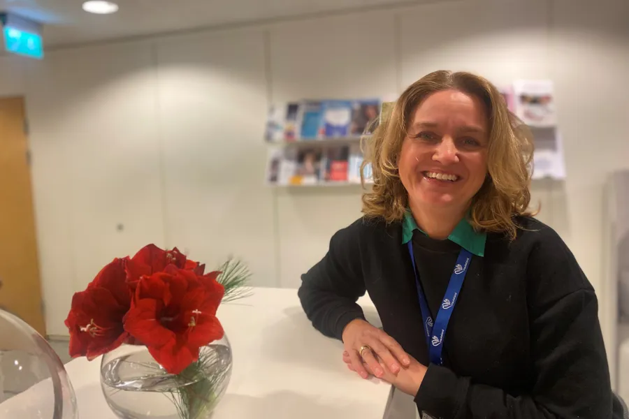 En person som smiler ved siden av en vase med blomster