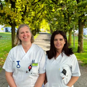 Et par kvinner iført hvite skjorter og stående i en park