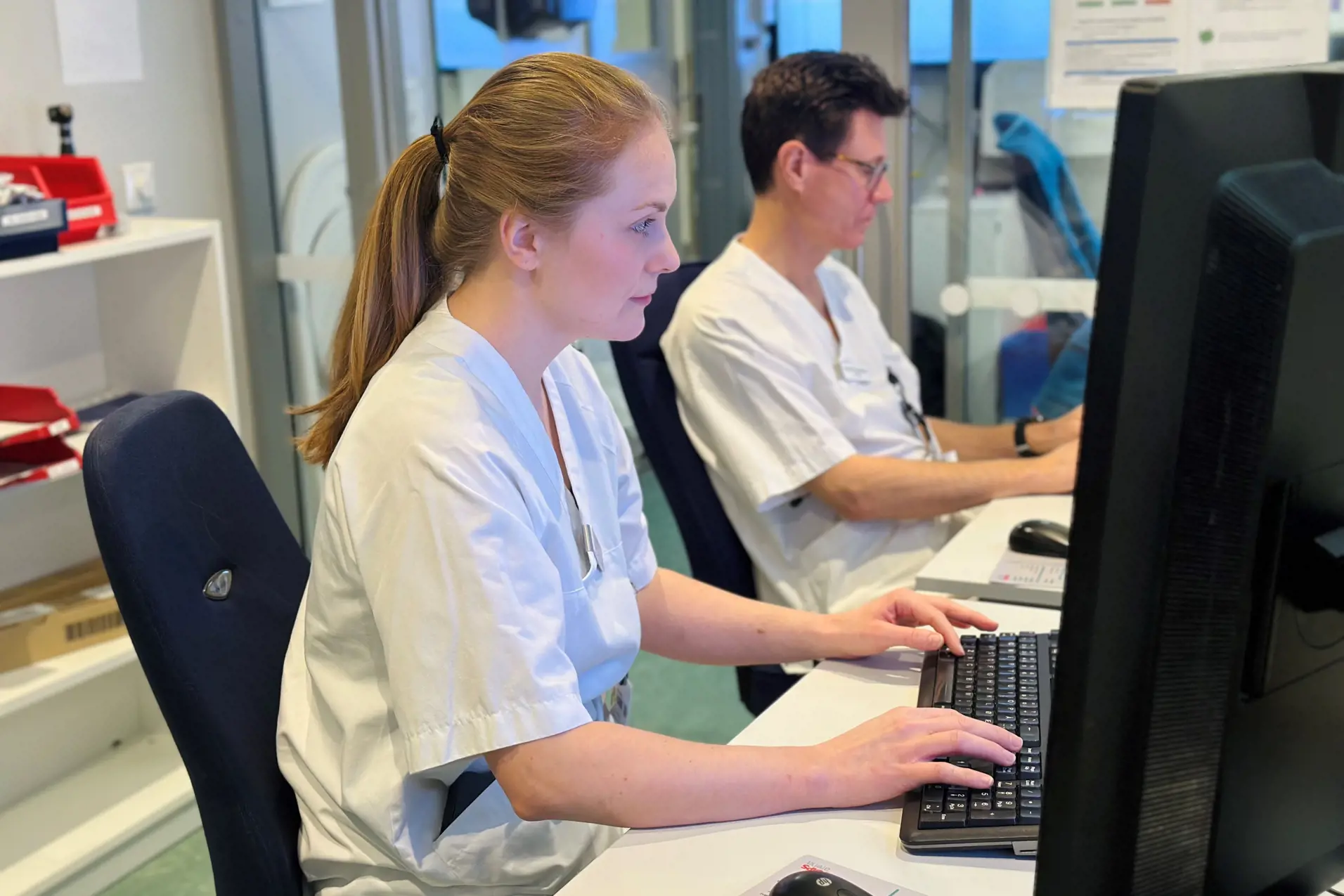 En lege og en pasient som arbeider på en datamaskin