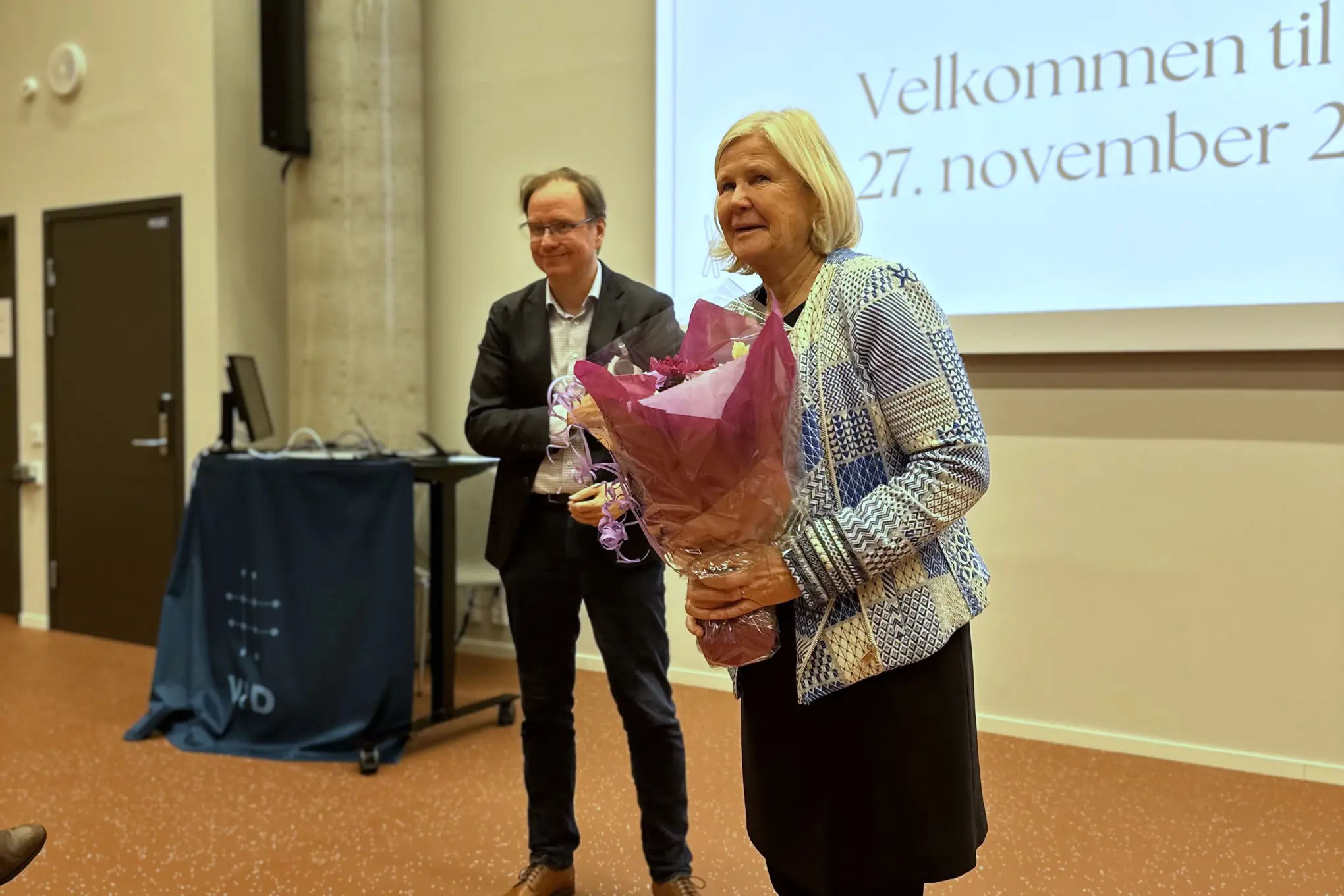 En mann og en kvinne som står foran en stor skjerm